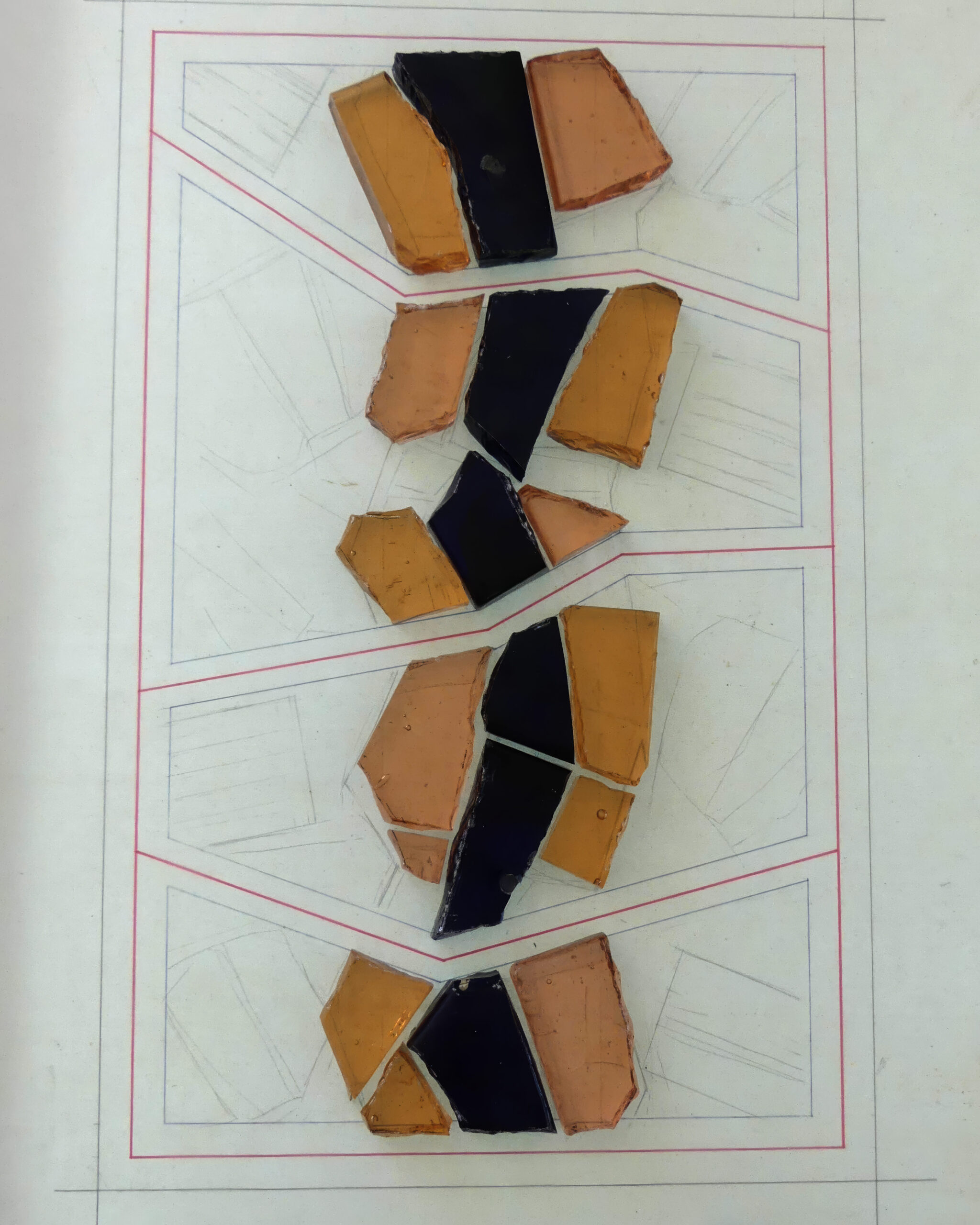 Vue sur des échantillons de dalles de verre taillées dans des nuances de bleu, d'ambre et de beige, disposées sur un carton technique à fond quadrillé.